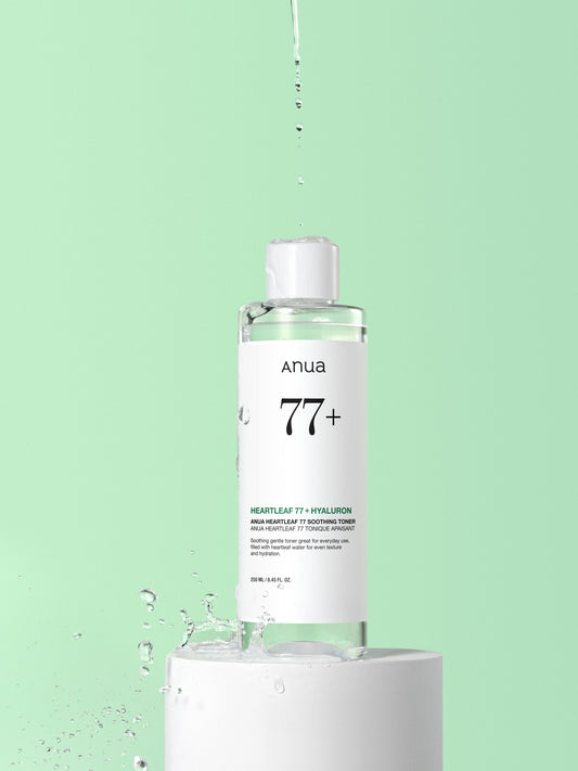 Anua Heartleaf 77% Soothing Toner 250ml - clear toner bottle dripping over a green background
