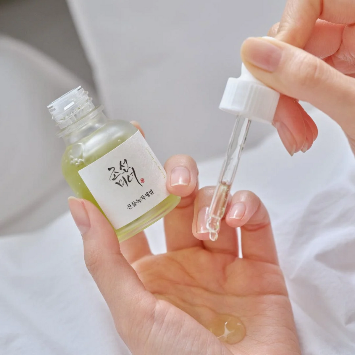 Beauty of Joseon Calming Serum Green Tea + Panthenol 30ml - hands holding the green serum bottle and dropper