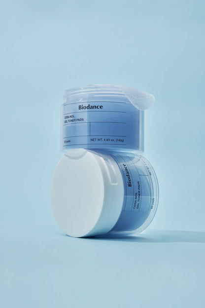Biodance Cera-NOL Gel Toner Pads 60 Pads 140g - blue jar with the lid set beside it, on a blue background