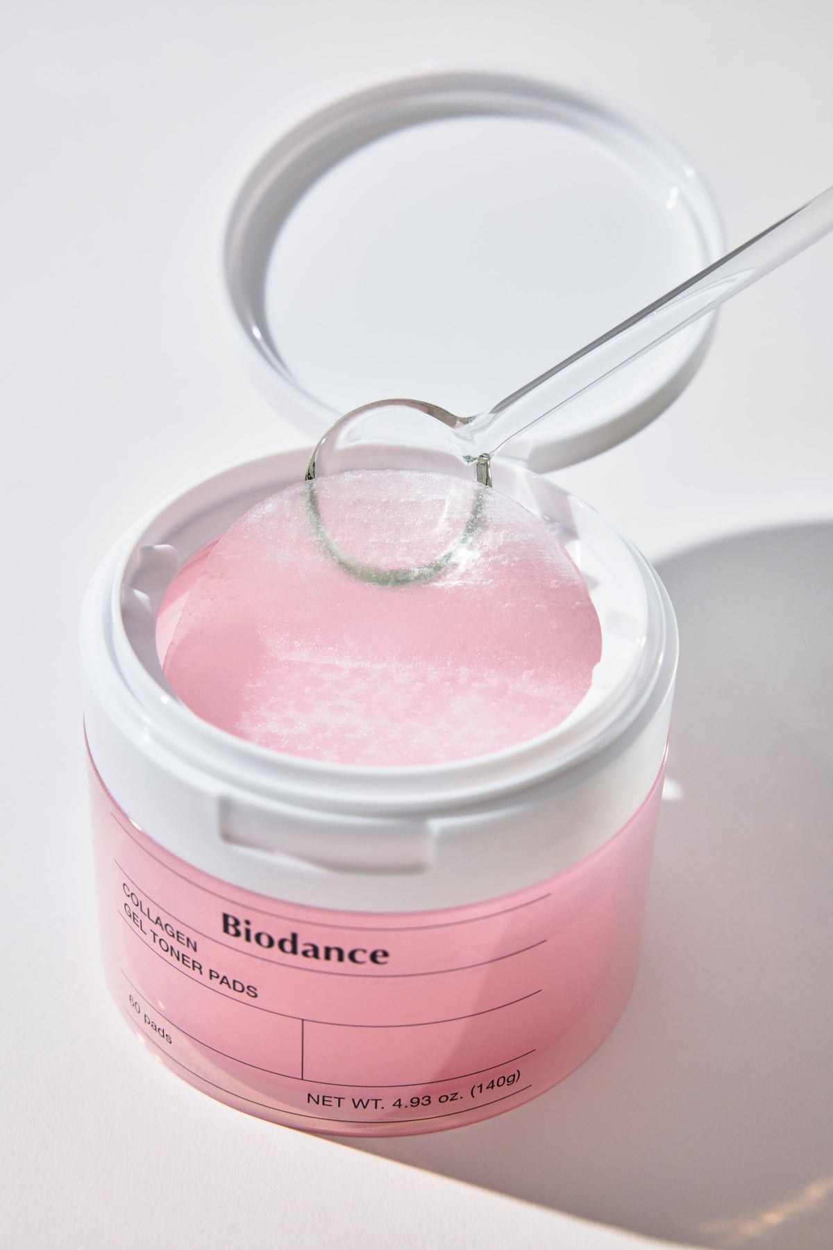 Biodance Collagen Gel Toner Pads 60 Pads 140g - open pink jar with tweezers lifting one gel pad, pale background