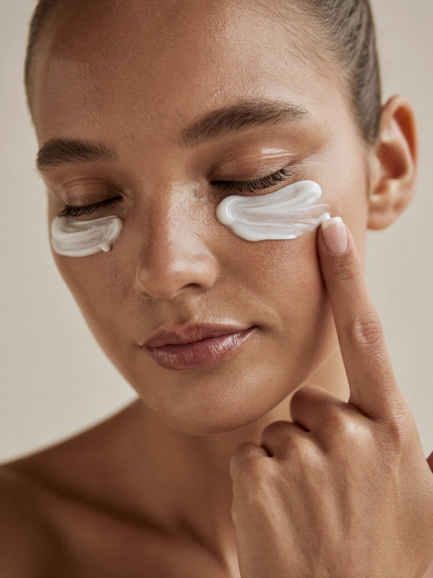 Model applying eye cream under the eyes