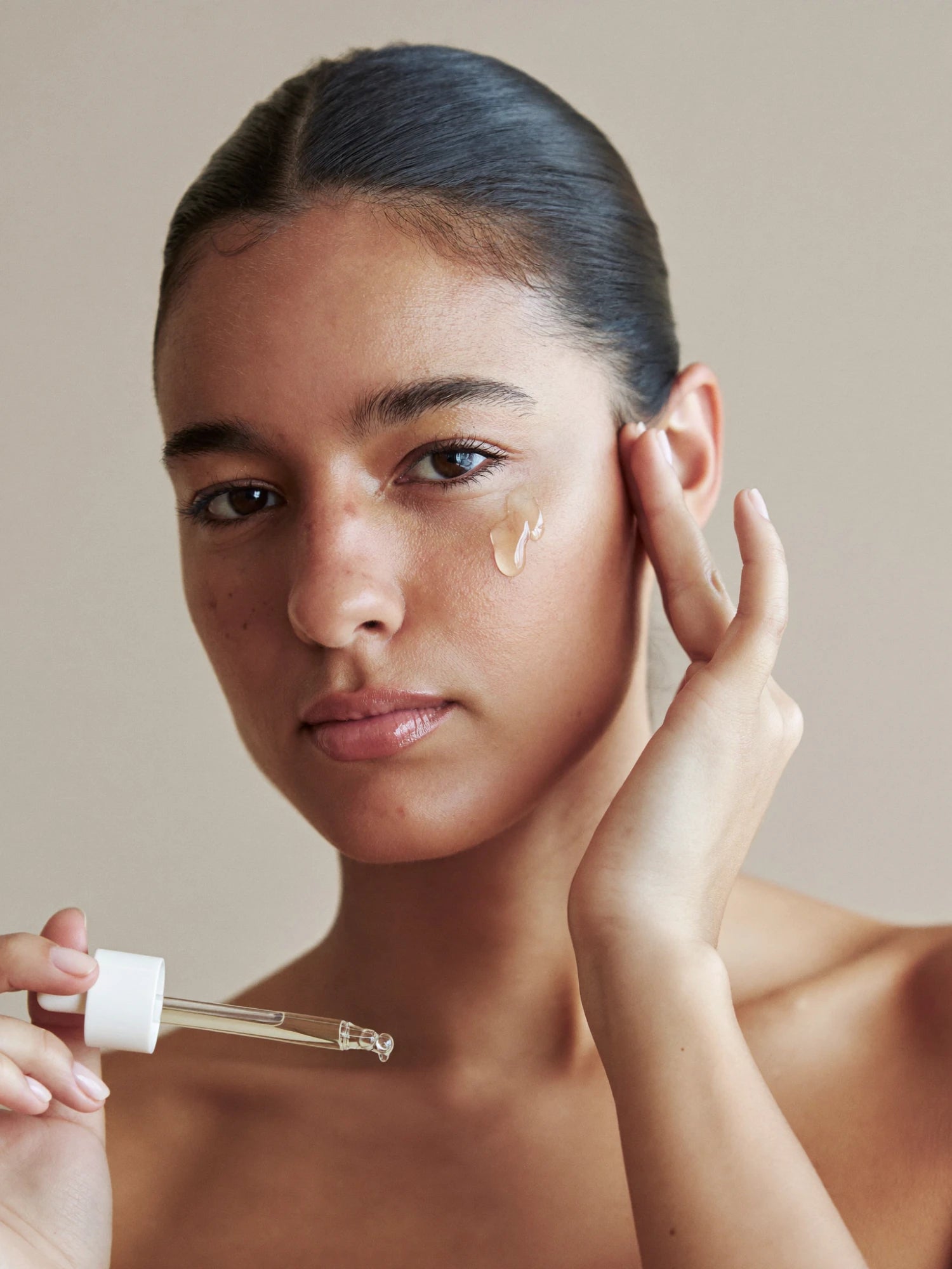 Model applying facial serum with a dropper
