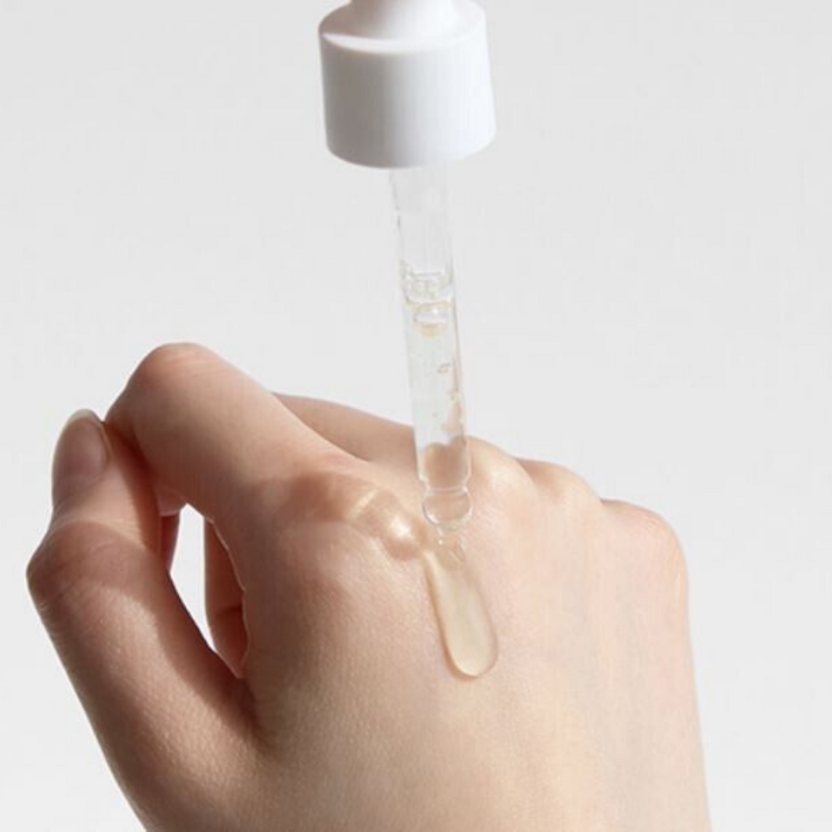 Dr.Althea Vitamin C Boosting Serum 30ml - a hand with a drop of the serum on the back, dropper above