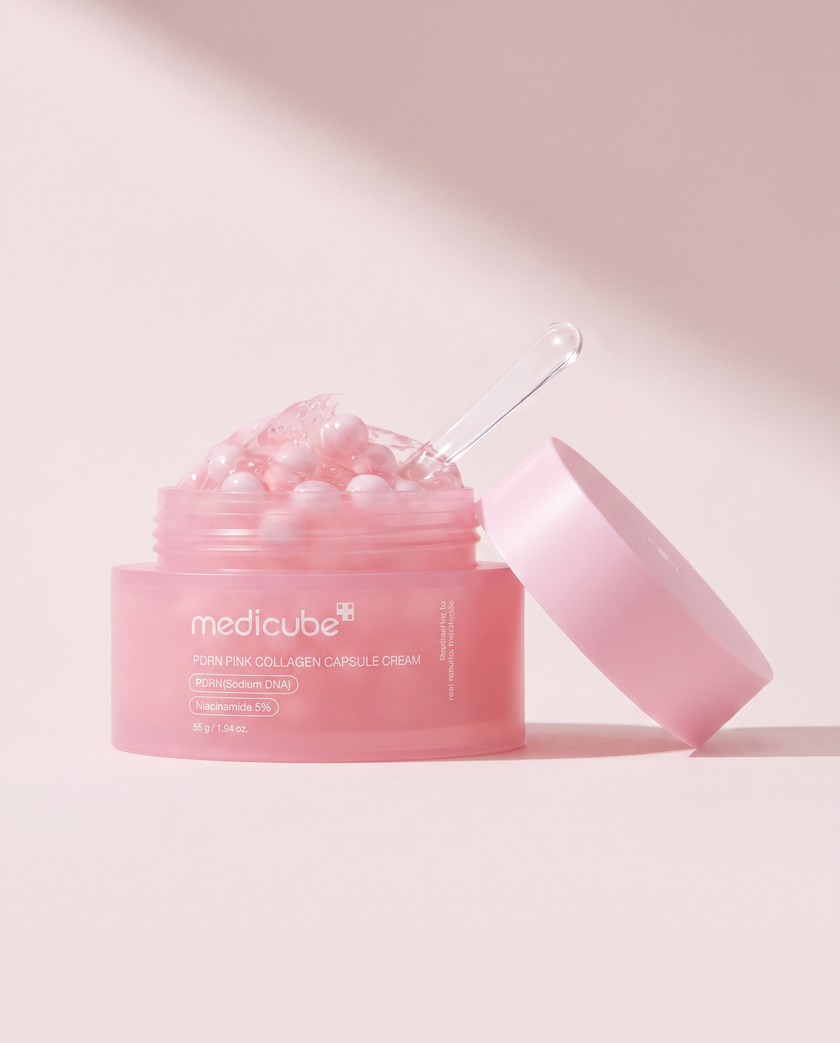 Medicube PDRN Pink Collagen Capsule Cream 55g - open pink jar with the lid propped beside it, pink background