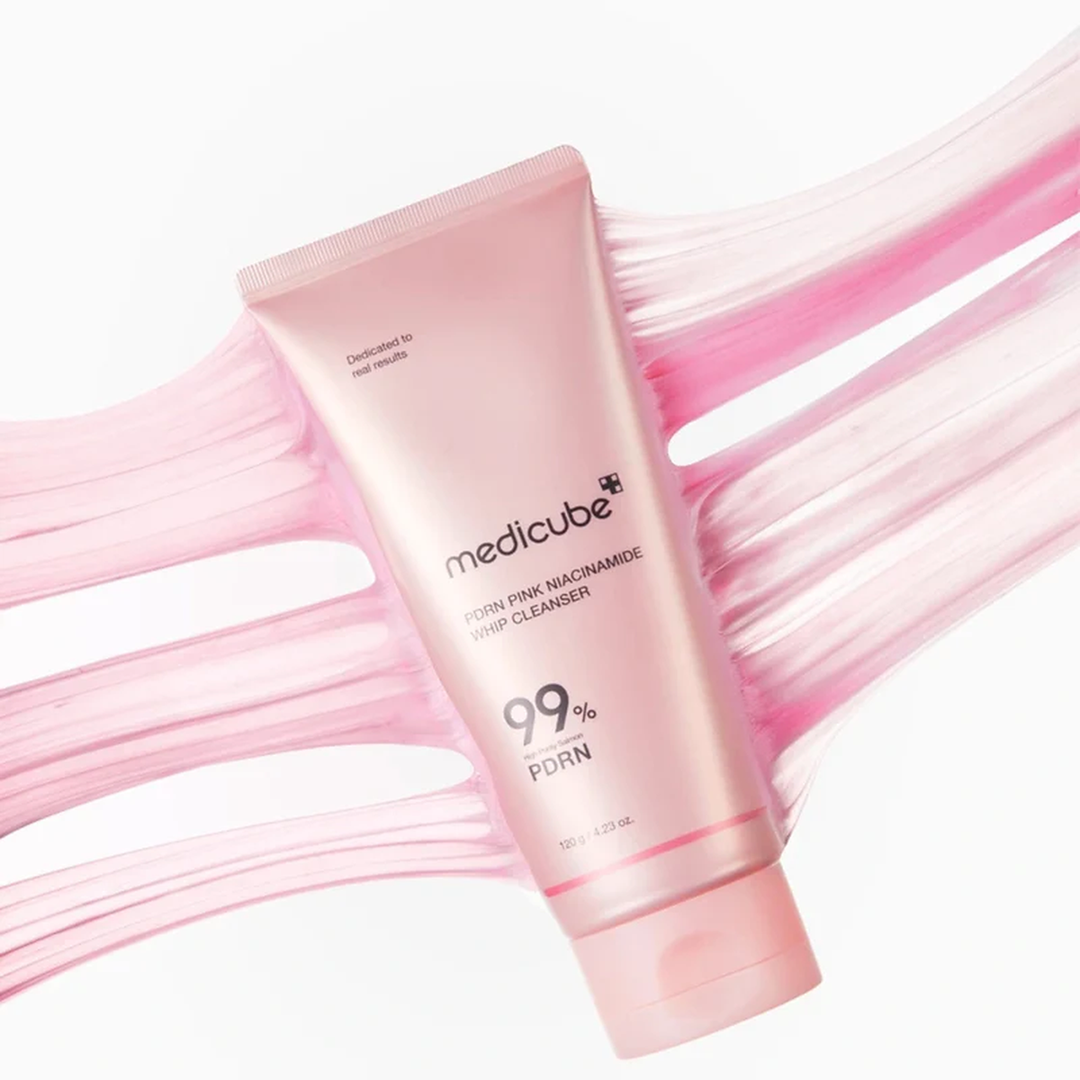 Medicube PDRN Pink Niacinamide Whip Cleanser 120g - pink cleanser tube laid on a stretchy pink texture swatch