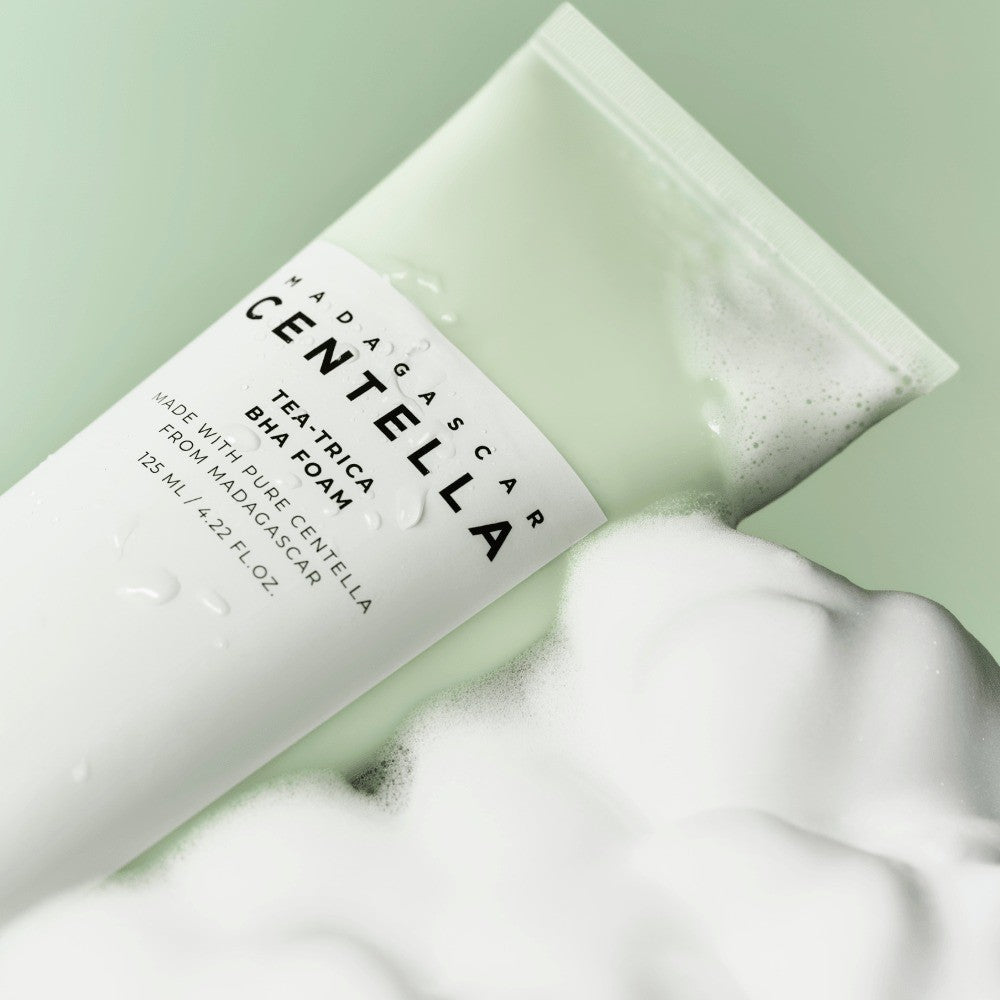 SKIN1004 Madagascar Centella Tea-Trica BHA Foam 125ml tube resting in a cloud of thick white foam on a mint-green background